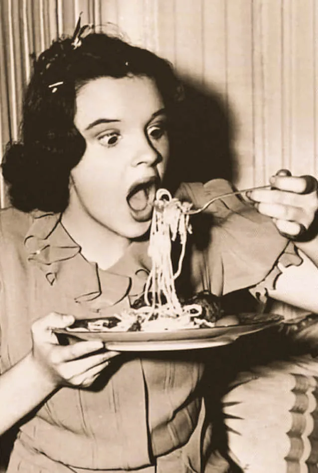 Mujer con gesto expresivo comiendo espaguetis en imagen vintage en sepia