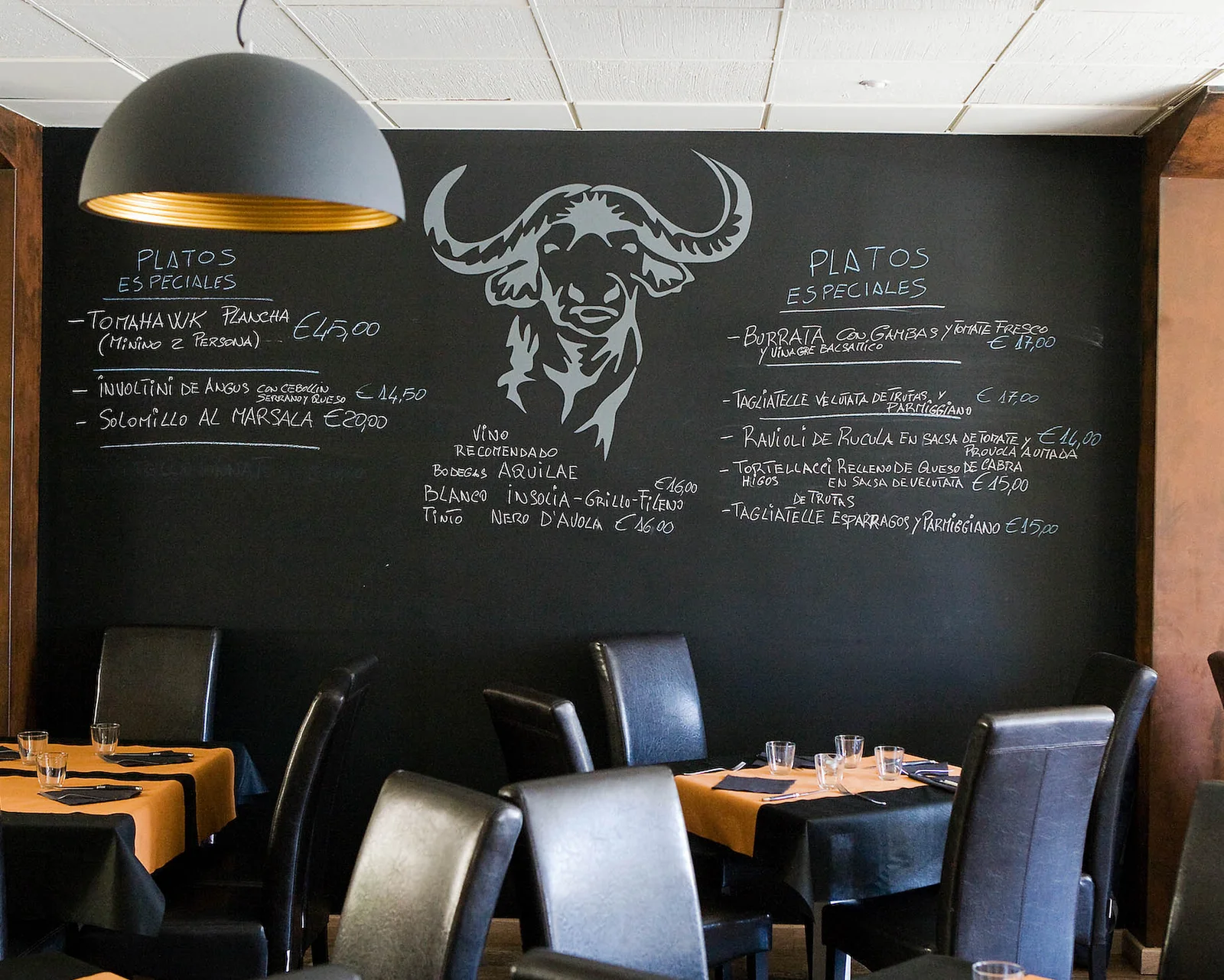 nterior de La Búfala de Alaró con mesas vestidas y pizarra ilustrada con cabeza de búfala