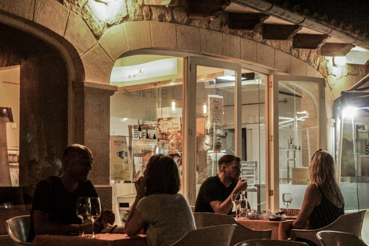 Fachada de La Búfala de Alaró con comensales cenando al aire libre por la noche